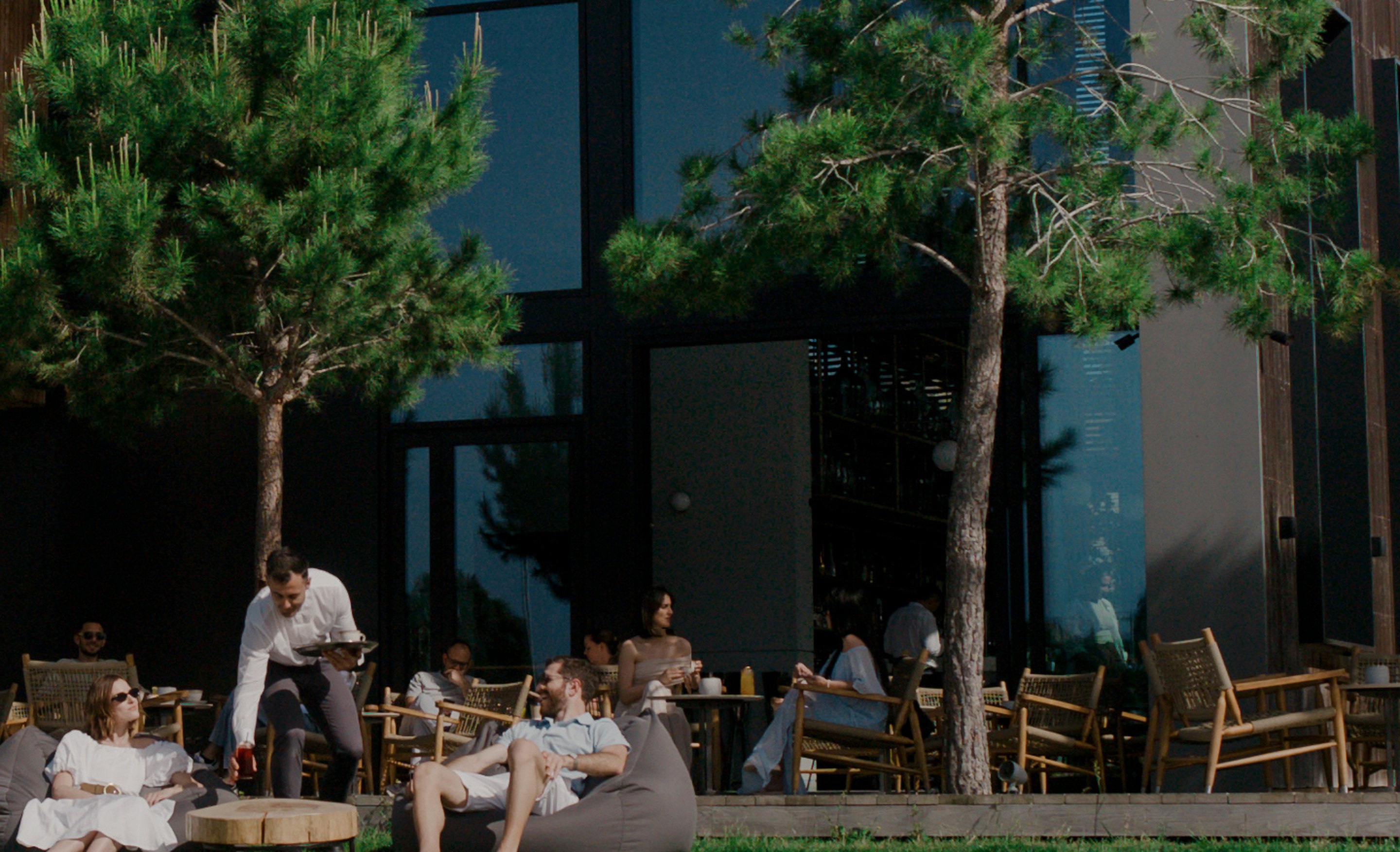 Guests at the Minthis clubhouse café terrace among pine trees